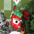Dettaglio di calza natalizia rossa con paillettes verdi e orsetto su un ramo di Natale - Orso Piccolo