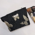 Dettaglio della trousse vintage con jacquard a farfalla dorata e chiusura a zip robusta - Nero Farfalla