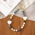 Detail of beaded phone strap with black square beads, white hearts and gold ring clasp - Crystal Heart Beaded Pendant / Black