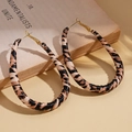 Close-up of leopard print leather teardrop earrings on a vintage book with warm shadows - Hoop Earrings - Coffee Brown - Teardrop Large
