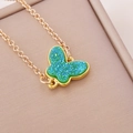 Golden chain necklace featuring a green butterfly pendant on a beige jewelry box edge - Lake Blue