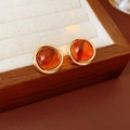 Macro detail of amber resin earrings with swirling gold frame on a jewelry tray - Steel Pin - Brown - Round