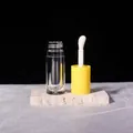 Macro shot of 6ml clear lip gloss tube with yellow cap and white brush applicator - 6ml / Yellow
