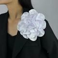 Detail of a large 19cm white satin floral brooch pinned on a black suit shoulder - White