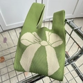 Green knit tote bag with large white bow pattern shown in a metal basket - Matcha Green Bow