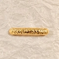 Detalle de pinza de pelo dorada con textura irregular sobre fondo de papel blanco - Clip de resorte martillado líquido / Dorado