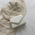 White V-quilted crossbody bag with elegant pearl strap and gold metal hardware - White