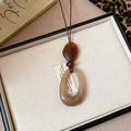 Détail d'un collier long vintage avec pendentifs géométriques sur plateau blanc - 5# Collier-Café-Ovale