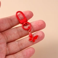 Detalle de un llavero de mariposa de metal rojo con acabado esmaltado y clip de muelle - Mariposa Roja