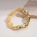 Macro detail of elastic beaded bracelet with irregular gold metal and amber resin beads - White