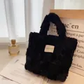 Dettaglio della borsa tote nera in peluche a nido d'ape con logo Hilldi Plan su tavolo - Nero