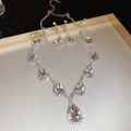 Macro shot of silver pear-cut gemstone jewelry set on a reflective tray - Large Pear Main Stone Halo Style / Silver