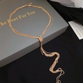 Detail van een gouden gelaagde slangenketting met knoopkwastje op een geschenkdoos - Goud
