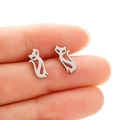 Primer plano de pendientes de gato plateados sobre un dedo para mostrar el tamaño real - Color Acero