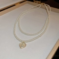 Close-up of double-layer pearl necklace with heart pendant in a beige jewelry box - White