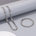 Detail view of silver titanium steel bone link chain necklace and bracelet on grey display - Steel