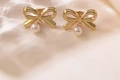 Elegant gold bow earrings with white pearl drops on soft silk fabric background - ED20-Bow Tie Dangle Pearl