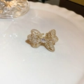 Close-up of golden bow-shaped open ring with micro-set zircons on a textured white plate - Bow Full Drill Open Ring / Gold