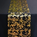 Detailed view of black polyester table runner with gold and green metallic foil pattern - Black Gold