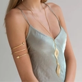 Detail of a long gold leaf body chain and spiral arm cuff on a model wearing a silk dress - Gold Leaf