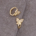 Macro detail van gouden vlinder oorbellen met sprankelende zirkonia op stenen achtergrond - Vlinder Zirkonia / Goud