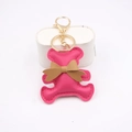 Close-up of pink PU leather bear keychain with brown bow and golden metal lobster clasp - Rose Red