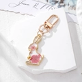 Detail of pink dried flowers inside a gold rabbit-shaped keychain with a metal clasp - Pink Flower Rabbit
