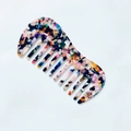 Detailed close-up of marble acetate wide-tooth comb with colorful tortoiseshell pattern - Colorful