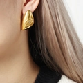 Orecchino a goccia dorato con design a occhio in rilievo e zircone indossato da modella - Oro