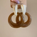 Detailopname van bruine kunsthars ringoorbellen met marmeren textuur op displaykaartje - Melkwit en Amber Gesplitste Ring