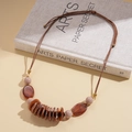 Macro detail of amber resin beads and acrylic oval pendants on a woven leather cord - Amber Coffee (Necklace-Coffee)