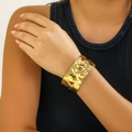 Polished gold hammered wide cuff bracelet with a textured punk style on a female wrist - Gold