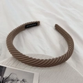 Detailed shot of brown ribbed fabric headband with handmade label on white textured background - Chocolate
