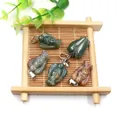 Natural angel stone pendants in assorted colors with silver metal clasp on bamboo tray - India Agate