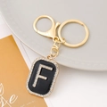 Detail of letter F keychain with black enamel and sparkling rhinestones on gold metal - Letter F