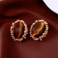 Detalle macro de pendientes vintage de oro con ojo de tigre sobre terciopelo oscuro - Poste de Pendiente de Plata Estilo de Clip de Oreja Oro Marrón