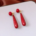 Dettaglio di orecchini rossi a goccia con borchie dorate su cartoncino d'esposizione - Perno in Argento 925/Metallo Dorato / Rosso