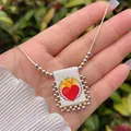 Detail van 18K vergulde kralenketting met een rechthoekige stoffen hanger met Heilig Hart - Heilig hart