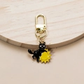 Macro detail of gothic black cat hugging sun metal keychain with golden clasp - Sun
