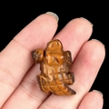Tiger's eye stone turtle carving held in hand with natural gemstone luster and texture - Tiger's Eye