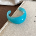 Macro shot of sky blue marble resin cuff bracelet on textured book with warm lighting - Wide Open Marble Style / Lake Blue