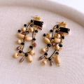 Détail de boucles d'oreilles vintage avec perles en bois et pompons de style bohème - Tige en argent - Or - Noir