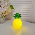 Cute yellow pineapple led night light with green leaves on white desktop - Pineapple