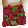 Detailed top view of deep red artificial rose gift box with velvet petals and green leaves - Burgundy