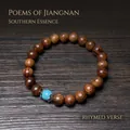 Bracelet en bois de santal avec perle turquoise sur un livre ouvert décoratif - Bois de Rose Noir 8mm avec Perle Turquoise