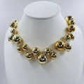 Close-up of a chunky gold ball necklace with a reflective mirror finish on a white bust - Gold