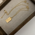 Gouden ketting met Maria-hanger en gekleurde zirkonia op een houten dienblad - Gegraveerd Goud Label (20221206SKXL-5)