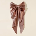 Detail of oversized satin bow hair clip with flowing long streamers in rose gold - Brown