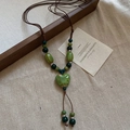Détail du pendentif cœur en céramique avec perles vertes sur cordon marron - Vert