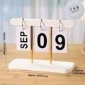 Minimalist white wooden flip calendar on desk with gold metal stand and assembly guide - Bamboo Calendar-White